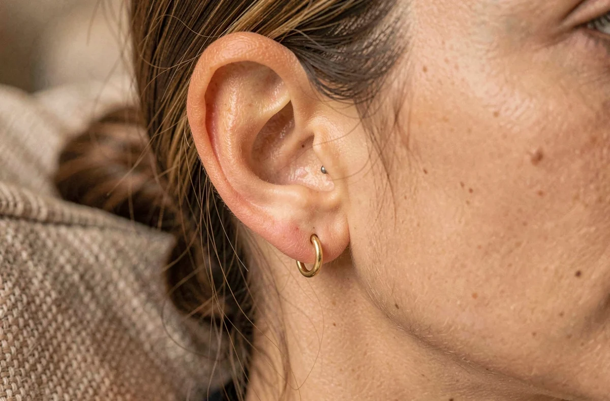Gros plan macro d'un piercing conch cicatrisé avec un anneau en or dans le cartilage de l'oreille
