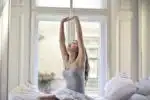 woman sitting on white bed while stretching